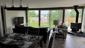 A living room with a sofa, a dining table set for four, a television, and a fireplace.