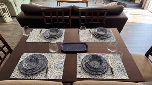 A dining table set with blue and white patterned tablecloths, a central serving tray, and wine glasses.