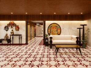 Um hall com piso estampado, um sofá, uma mesa e estátuas decorativas.