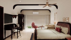 Een moderne slaapkamer met een bed, bureau, stoel, plafondventilator en een televisie.