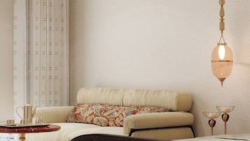 A modern bedroom with a bed, a sofa, a side table, and a hanging light fixture.