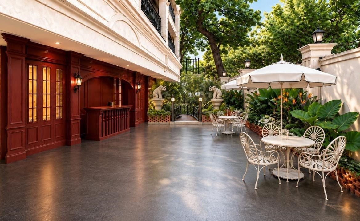 Un corridoio d'hotel con area bar, posti a sedere all'aperto con ombrelloni e vista sul giardino.