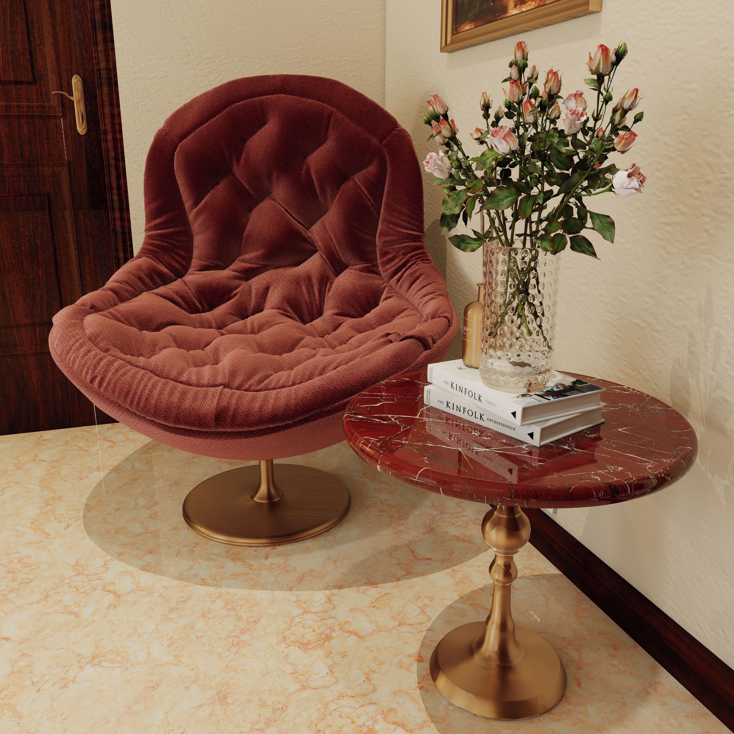 A plush red chair with a cushioned seat and backrest, positioned next to a marble table with a gold base. A vase with pink roses and a book titled 'The Kinfolk Table' are on the table.