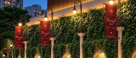 A building facade with vertical gardens, arched windows, and illuminated banners.