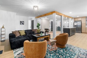 Ein modernes Wohnzimmer mit einer schwarzen Couch, orangefarbenen Sesseln und einem Couchtisch.