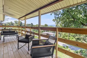 Un espacio de estar al aire libre cubierto, con mobiliario de madera y vista a un barrio residencial.