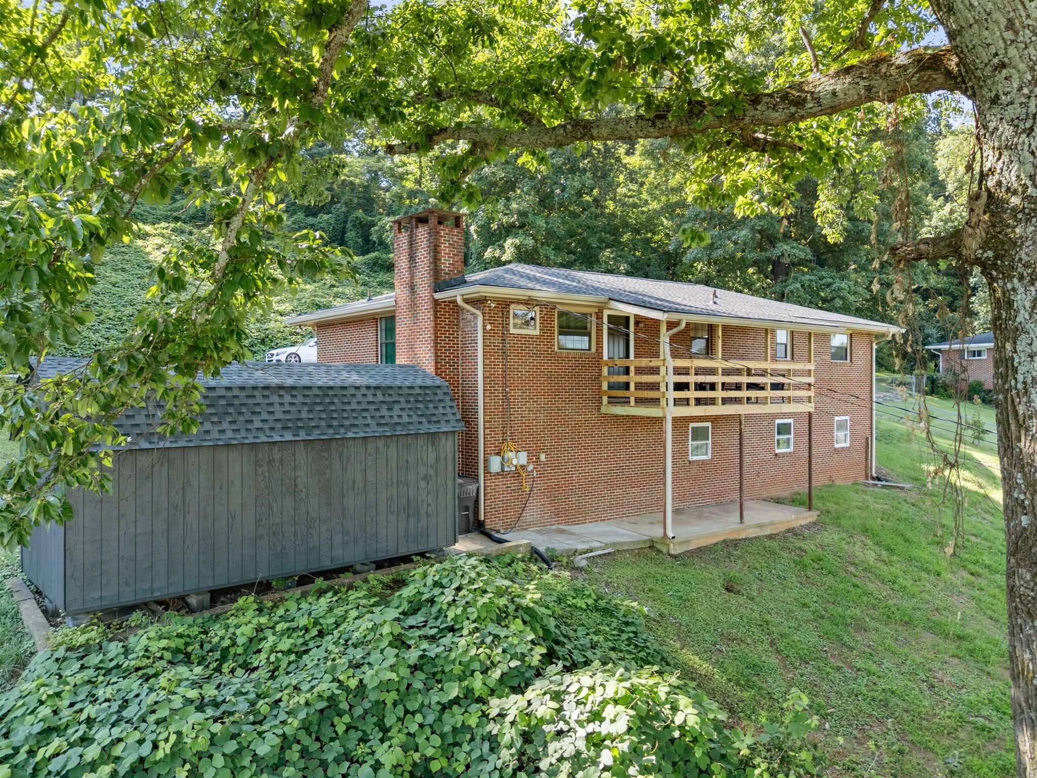 Ein einstöckiges Backsteinhaus mit überdachter Veranda und einem Gartenhaus.