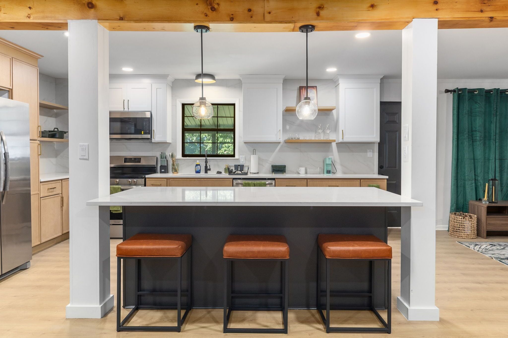 Una cocina moderna con una isla grande, taburetes de bar e iluminación colgante.