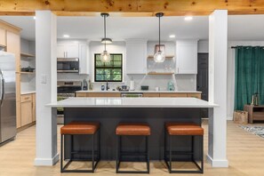 Una cocina moderna con una isla grande, taburetes de bar e iluminación colgante.