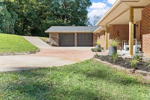 A residential property with a brick house, a garage with double doors, a covered porch with outdoor furniture, and a well-maintained lawn. - Family Retreat with Valley views and 2-Car Garage (Rossville)
