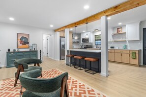 Una cocina moderna con una isla central, taburetes de bar y un comedor con sillas.