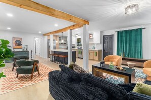 A modern living room with a sofa, armchairs, and a coffee table. There is a kitchen in the background with a dining area. - Family Retreat with Valley views and 2-Car Garage (Rossville)