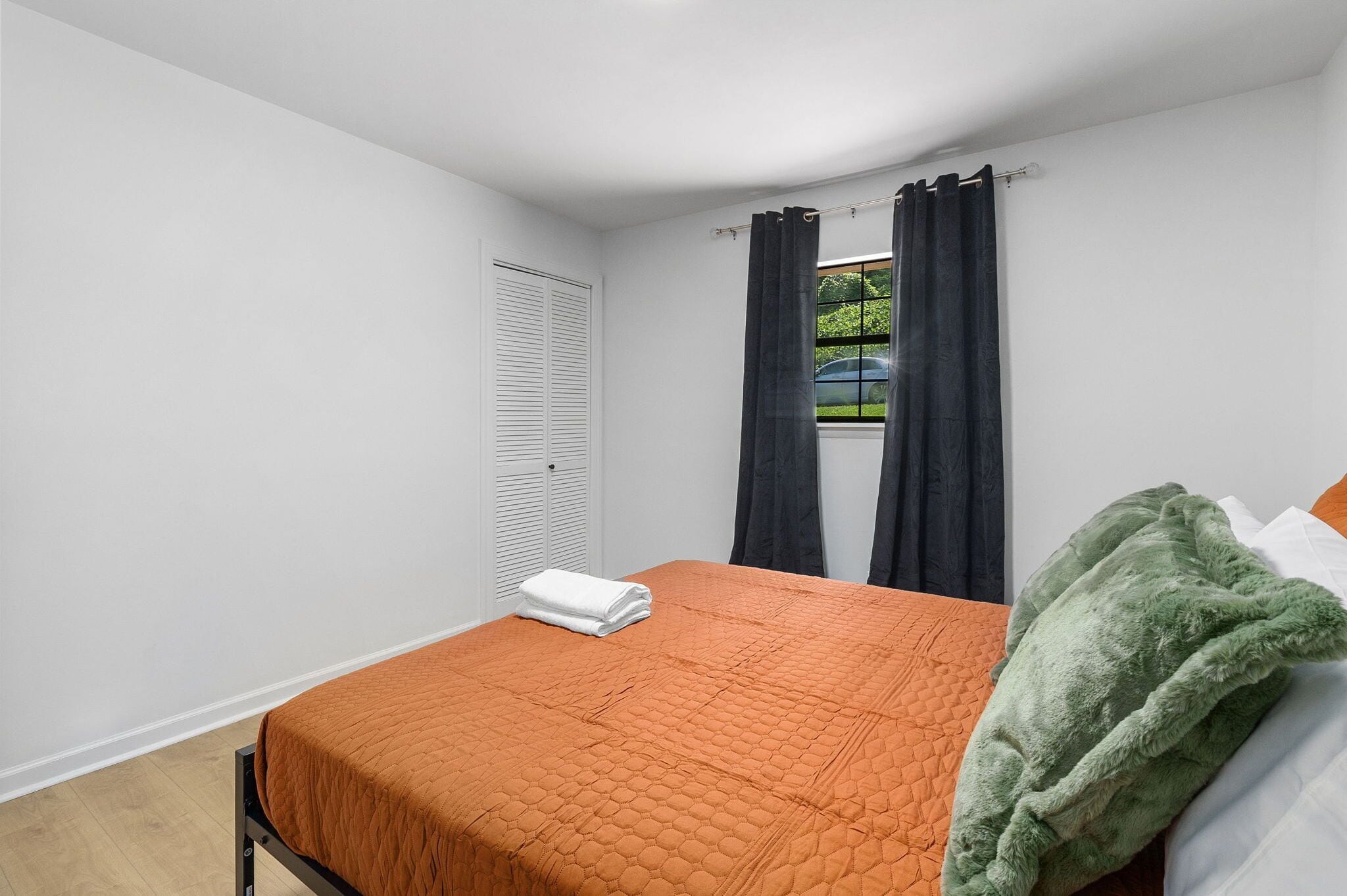 Quarto com uma cama, janela com cortinas, radiador e vista para o exterior.