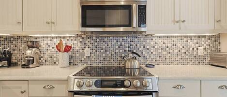 A kitchen with a microwave, stove, and coffee maker.