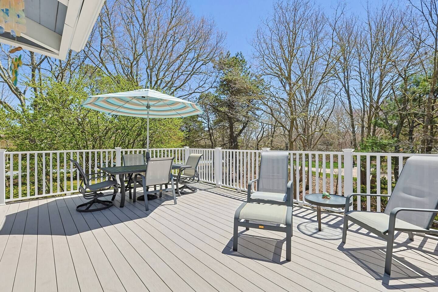 Eine Terrasse mit Gartenmöbeln, darunter ein Tisch und Stühle, sowie ein Sonnenschirm.