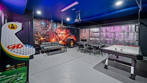 Una habitación con mesa de billar, un sofá y una pared decorada con un espectáculo de fuegos artificiales.