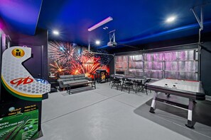 A room with a billiards table, a sofa, and a wall with a firework display. - Heron by Nest Villas | Entertainers Dream Backyard (Indio)
