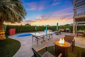 Eine Terrasse mit Pool, Gartenmöbeln und einem Feuerkorb.