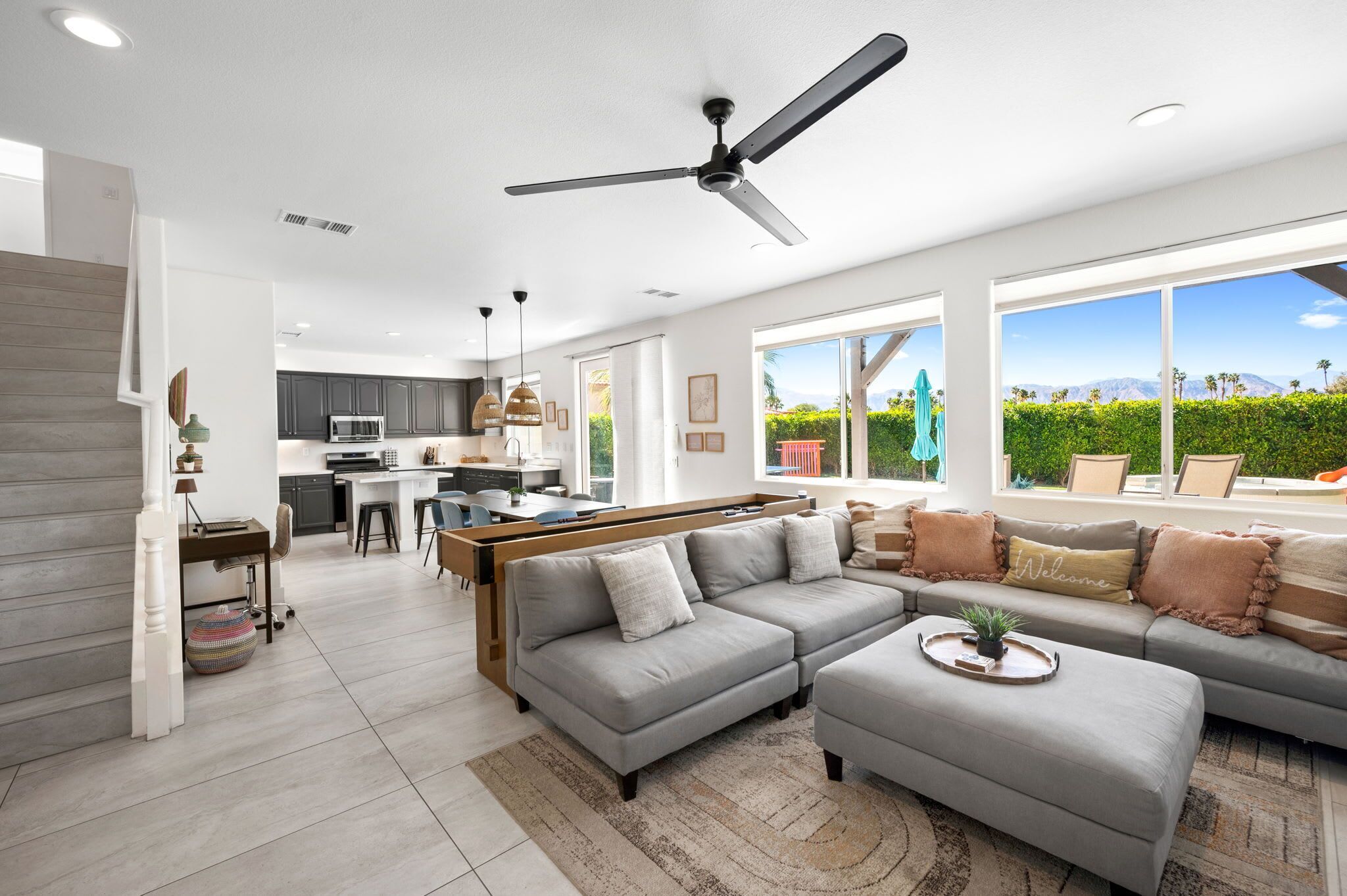 A modern living room with a grey sofa, a coffee table, and a dining area with a kitchen in the background.