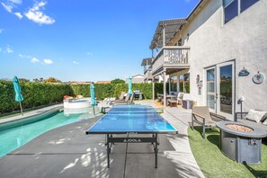 A swimming pool with a table tennis table, lounge chairs, and a barbecue area. - Heron by Nest Villas | Entertainers Dream Backyard (Indio)