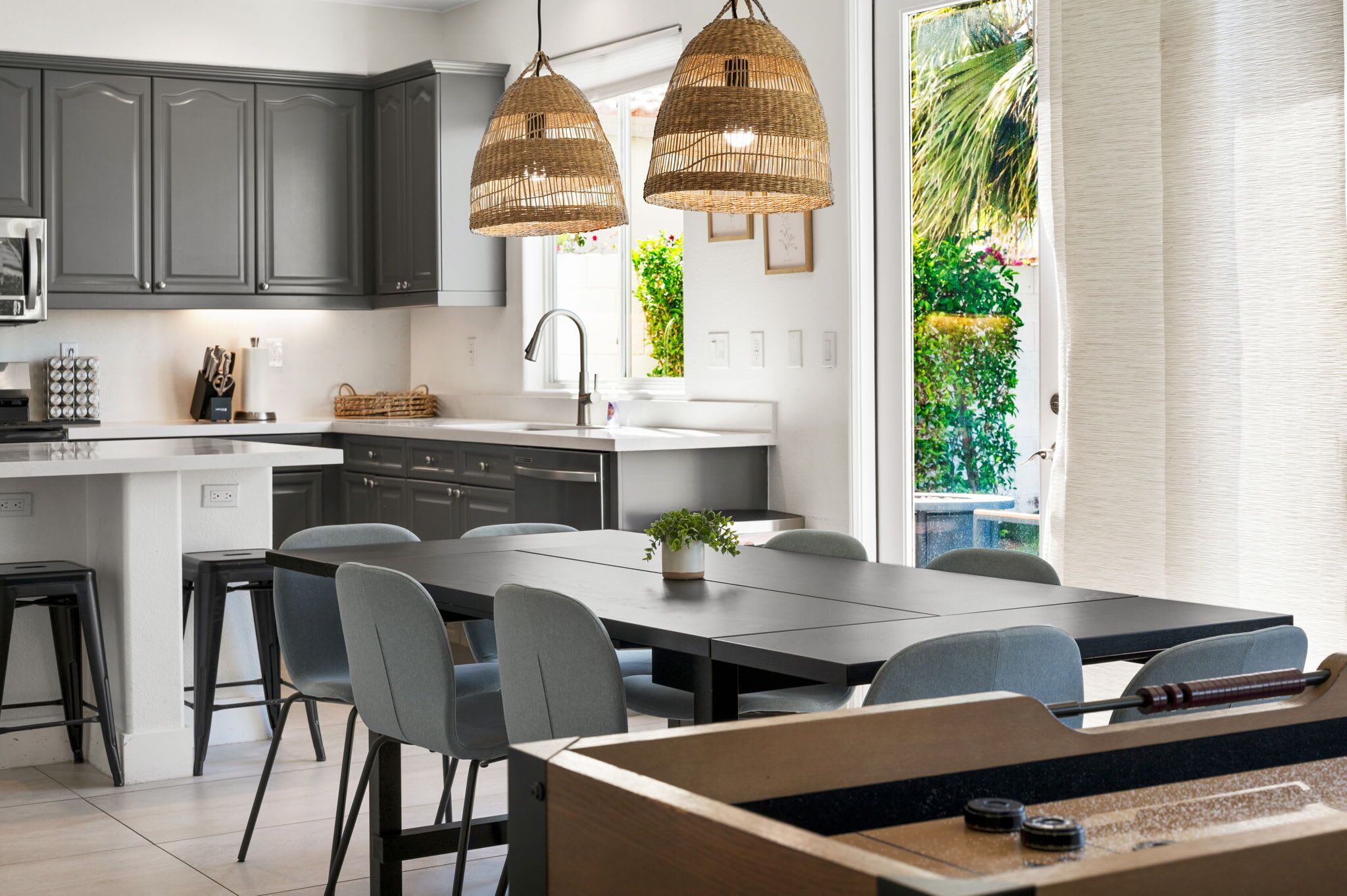 Une cuisine moderne avec des meubles gris, un plan de travail blanc et un coin repas comprenant une table et des chaises.