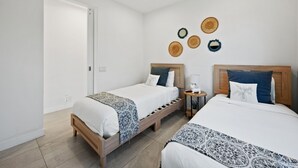 Hotellihuone, jossa on kaksi sänkyä, kattotuuletin ja koristeellisia seinäkoristeita.