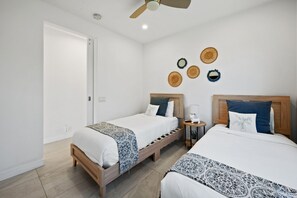 Ein Hotelzimmer mit zwei Betten, einem Deckenventilator und dekorativen Wandgestaltungen.
