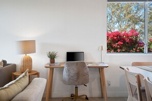 Ein moderner Arbeitsraum mit Schreibtisch, Stuhl und einem Fenster mit Blick auf rosa Blumen.
