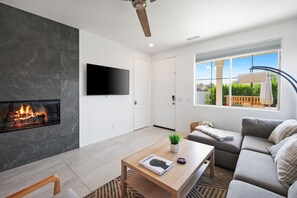 Ein modernes Wohnzimmer mit Kamin, Flachbildfernseher, Sofa und Couchtisch.