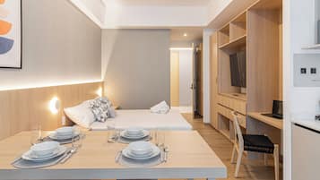 Una habitación de hotel moderna con zona de comedor, cama y kitchenette.