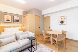 A modern hotel room with a sofa, a small table, a dining area with chairs, and artwork on the walls. - Myla Magnolia (Ciudad de México)