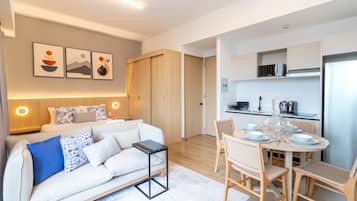 Una sala moderna con sofá, una mesa de centro y un comedor con sillas y una mesa dispuesta para una comida.