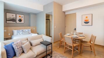 Una habitación de hotel moderna con cama, sofá, mesa de comedor con sillas y obras de arte en las paredes.