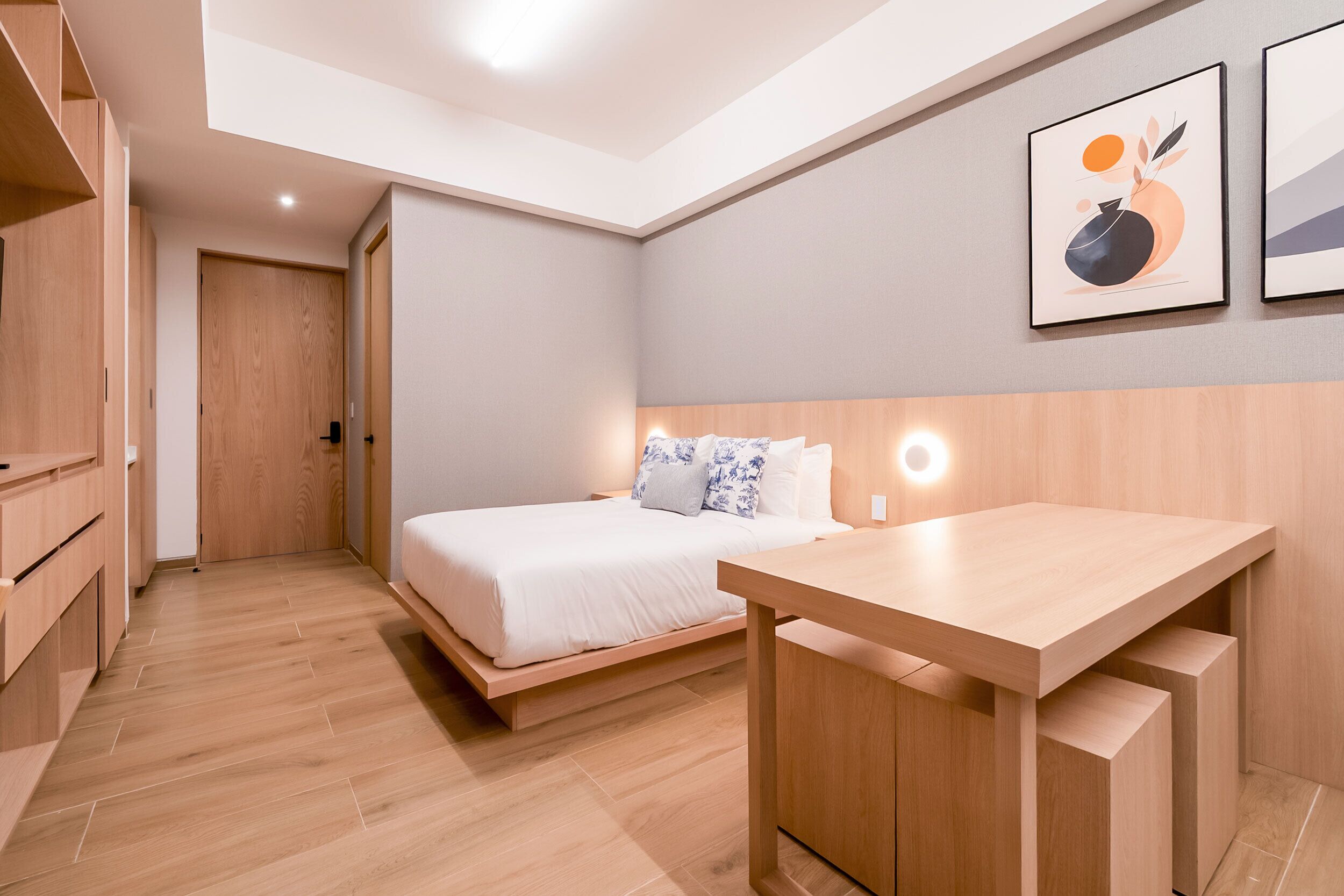 A modern bedroom with a bed, bedside table, and a wall-mounted light fixture.