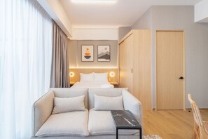 A modern hotel room with a bed, a sofa, a small table, and two wall-mounted artworks. - Myla Magnolia (Ciudad de México)