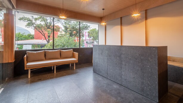 A modern interior with a sofa, a reception desk, and large windows.
