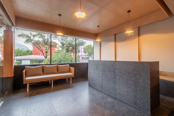 A modern interior with a sofa, a reception desk, and large windows.