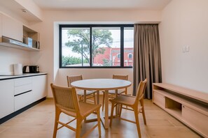 A modern kitchen with white cabinets, a round dining table, and wicker chairs.