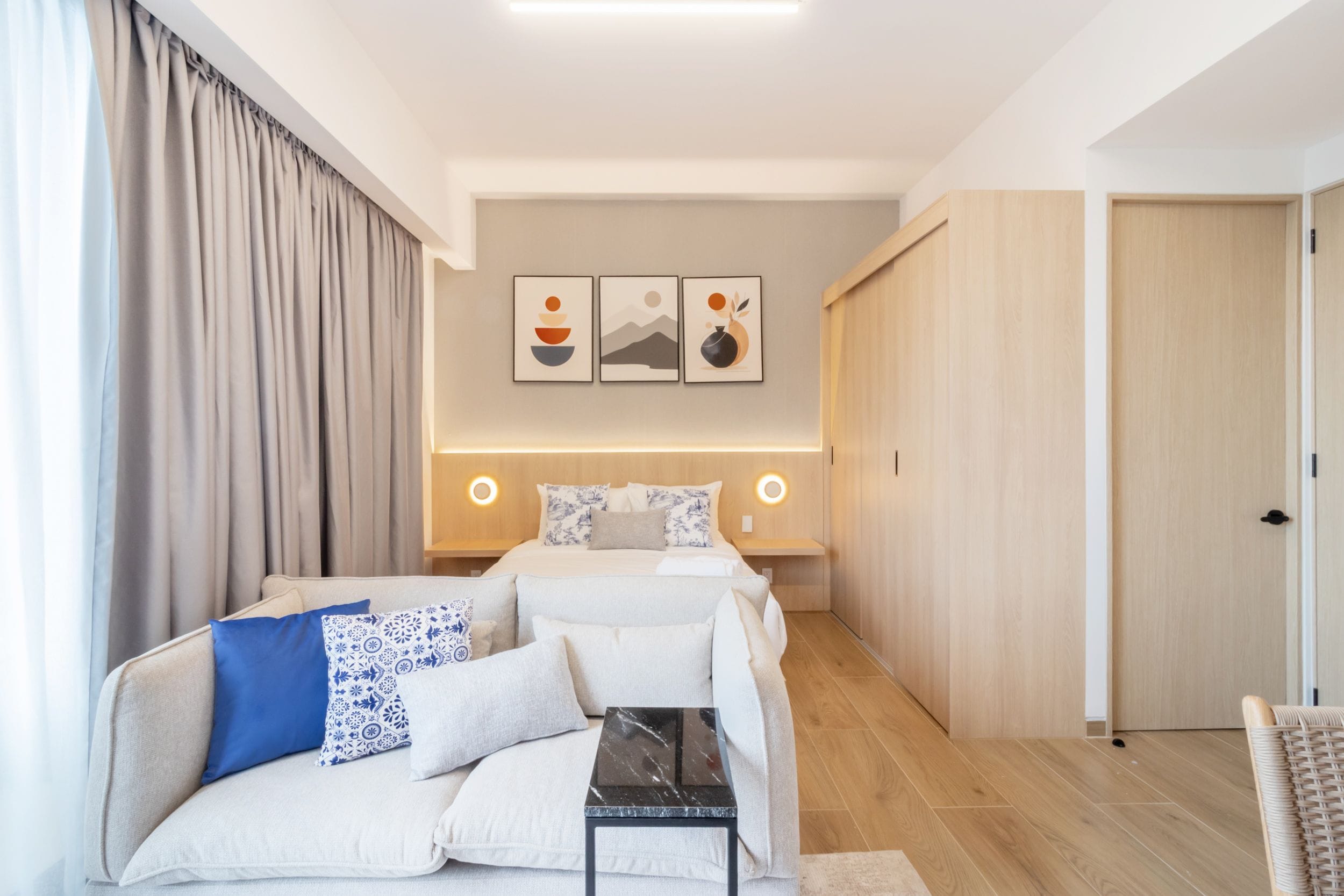 Habitación de hotel moderna con cama, sofá, una mesita y obras de arte en la pared.