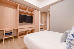 A bedroom with a bed, a TV, a desk, and a wardrobe.