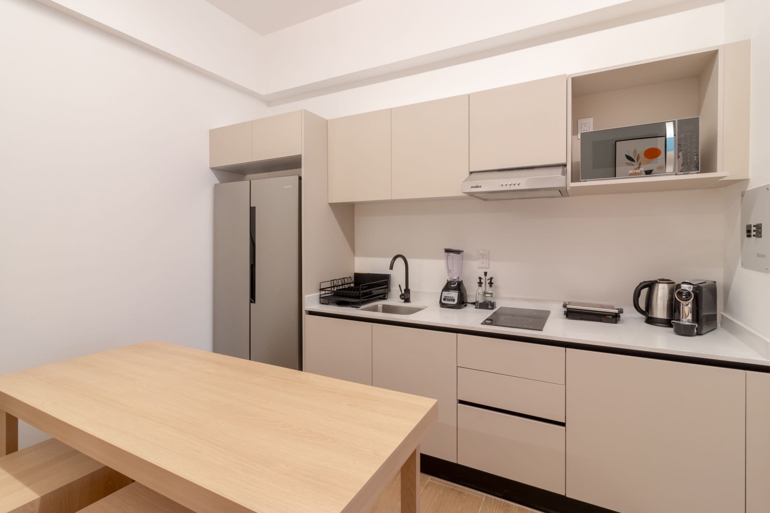 A compact kitchen with a built-in refrigerator, a stove, a microwave, and a coffee maker.