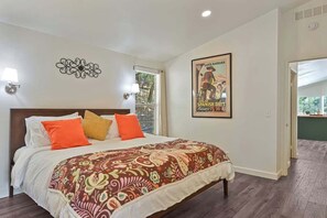 A hotel room with a large bed, a poster on the wall, and a view of the outdoors. - Maple Ring Kenwood Cottage (Kenwood)