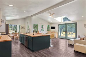 A spacious kitchen with a central island, wooden flooring, and a ceiling fan. - Maple Ring Kenwood Cottage (Kenwood)