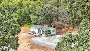 A single-story house with a porch, surrounded by dense trees. - Maple Ring Kenwood Cottage (Kenwood)