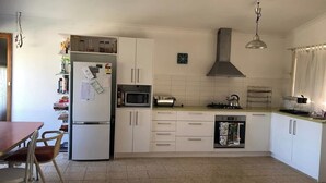 Eine Küche mit weißen Schränken, einer Mikrowelle, einem Herd und einem Kühlschrank.