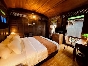 Habitación de hotel con cama, escritorio, silla, televisor y ventana con vista.