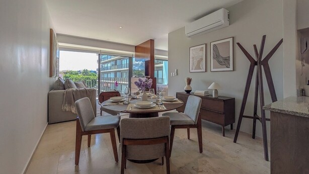 A modern dining area with a round table, chairs, and a view of the outdoors. - Mr. W | Bright and Modern 1-Bedroom | Zentral Tower (Zapopan)