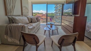 A modern living room with a sofa, two chairs, a small table, and a TV. - Mr. W | Bright and Modern 1-Bedroom | Zentral Tower (Zapopan)