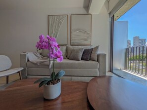 Ett modernt vardagsrum med en soffa, ett soffbord och en orkidé i en kruka.