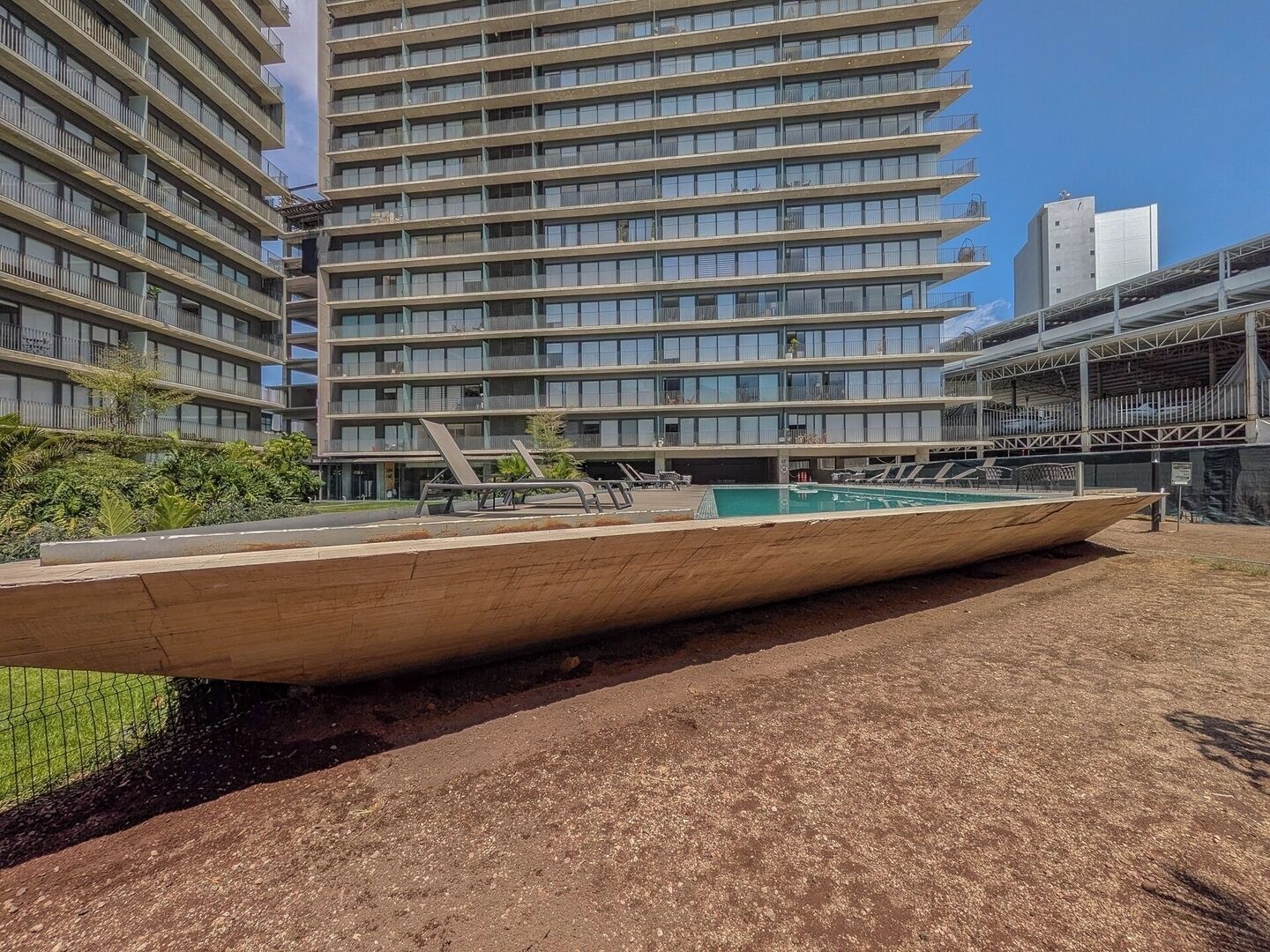 Un edificio moderno con varios balcones y una zona de piscina.
